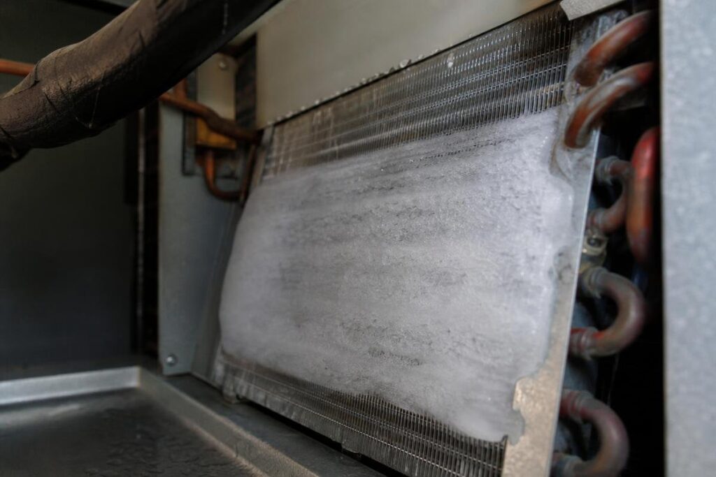 Close-up of an air conditioning evaporator coil with visible ice buildup, indicating a possible malfunction or airflow problem.