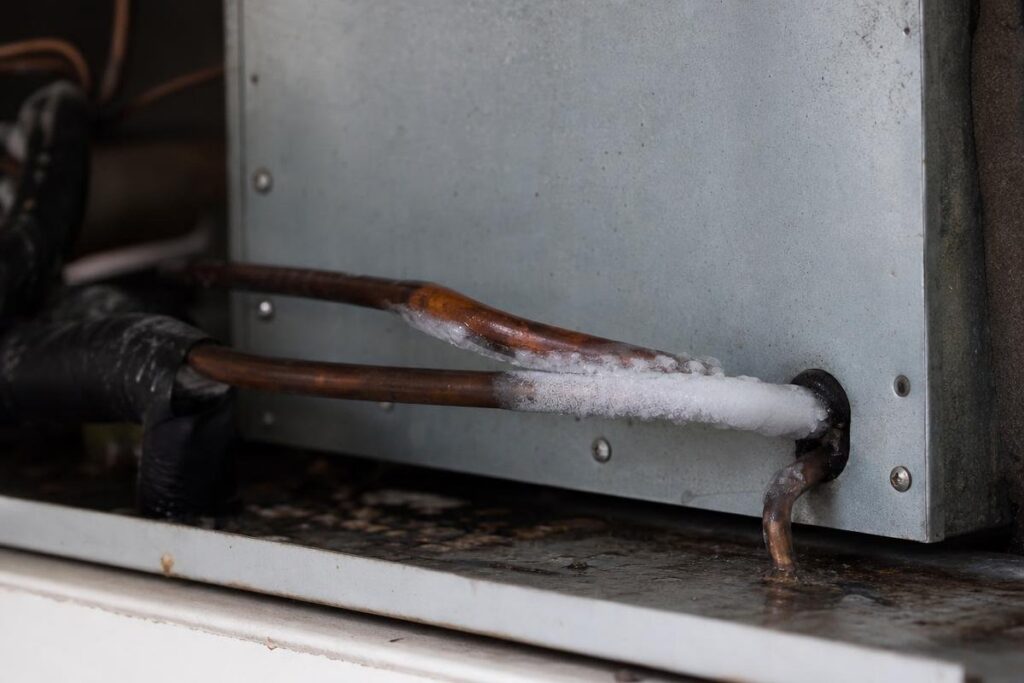Frost forms on copper pipes connected to a metal HVAC unit, indicating a potential issue with the air conditioning system.
